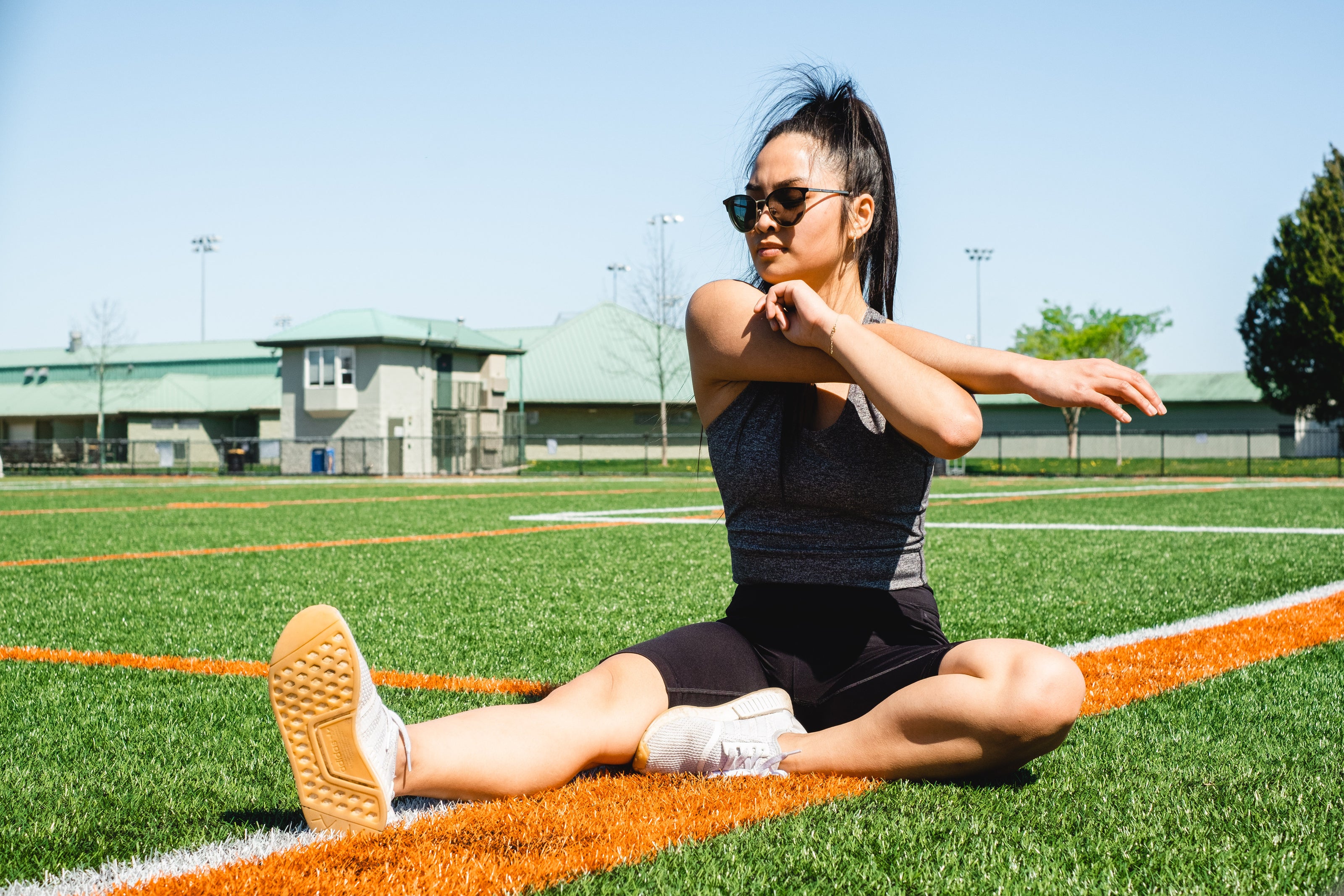 Woman stretching on a sports field representing functional human movement and the principle of athletic performance — Auralis Movement